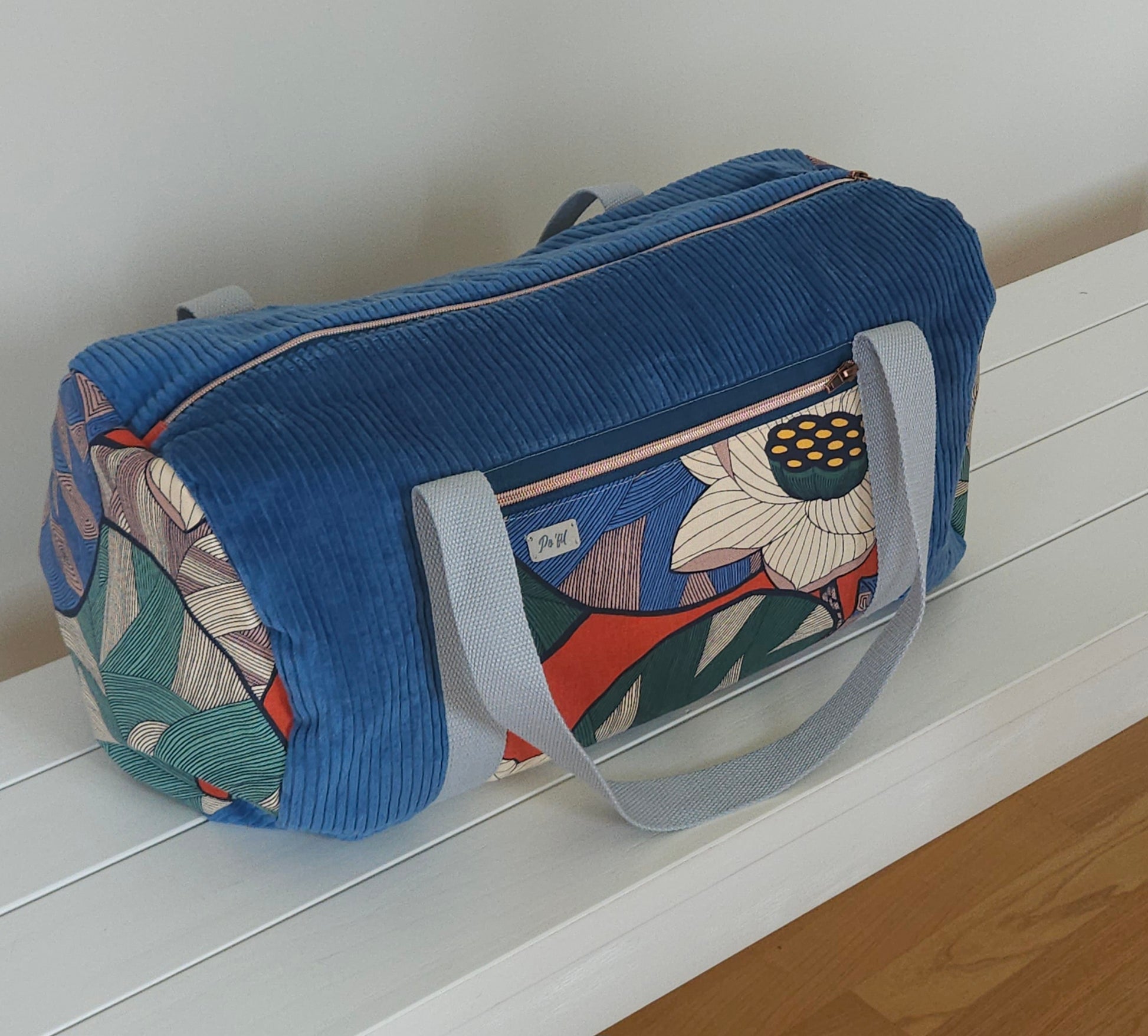 Sac polochon en velours côtelé - création artisanale unique- fait-main en Haute-Loire. Marque Po'Fil. Velours bleu et tissu motif fleuri. poignets anse de coton épais. 
